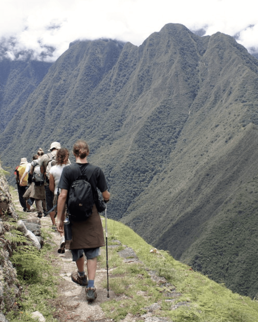 Viajeros caminando el Camino Inca hacia Machu Picchu durante trekking en los Andes