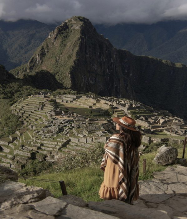 Mujer con sombrero y poncho observando Machu Picchu, una de las siete maravillas del mundo