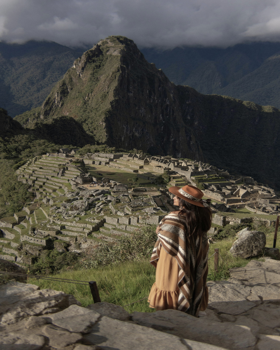 Mujer con sombrero y poncho observando Machu Picchu, una de las siete maravillas del mundo