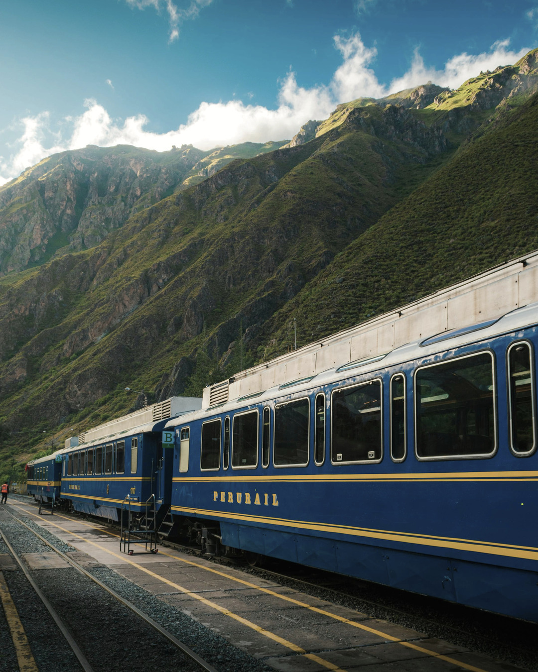 Tren PeruRail recorriendo paisajes verdes andinos en ruta hacia Machu Picchu