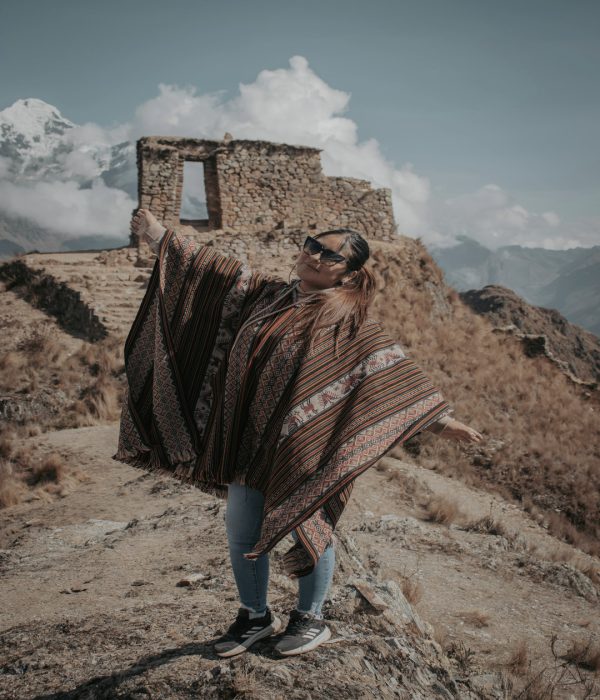 Mujer con poncho peruano frente a montañas en el Valle Sagrado de los Incas