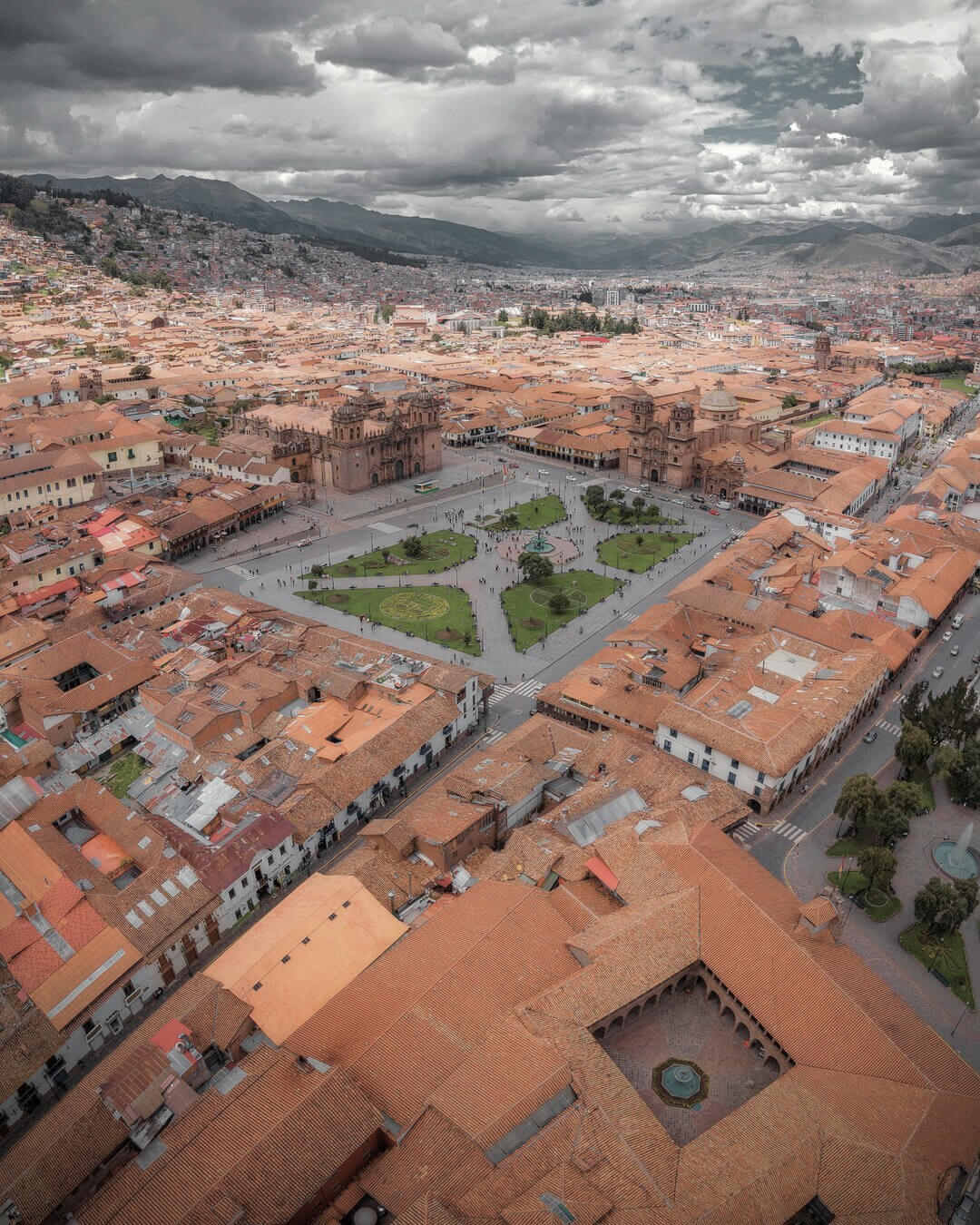 Vista aérea con dron de la Plaza de Armas de Cusco rodeada por iglesias coloniales y edificios históricos.